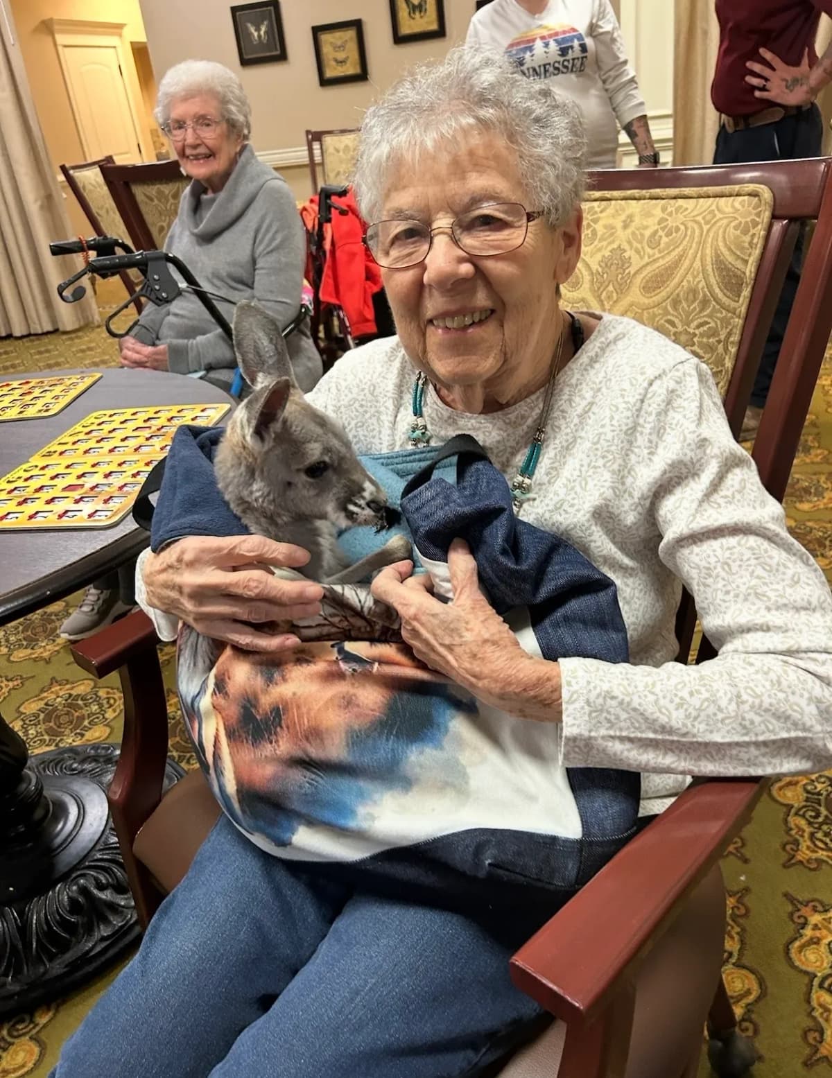 Elderly resident holding Sophie the baby kangaroo